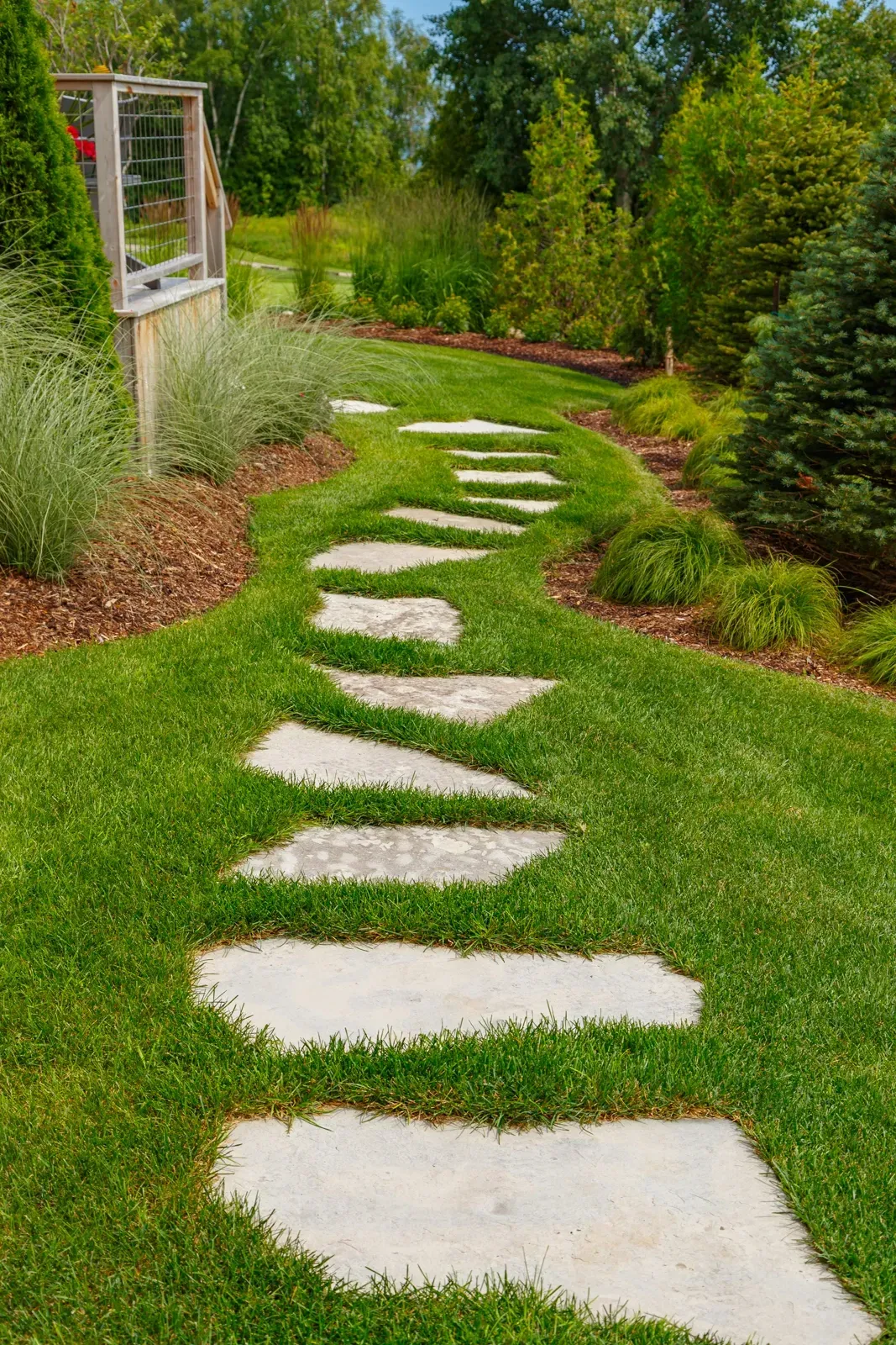 A stone walkway going through a lush green garden.