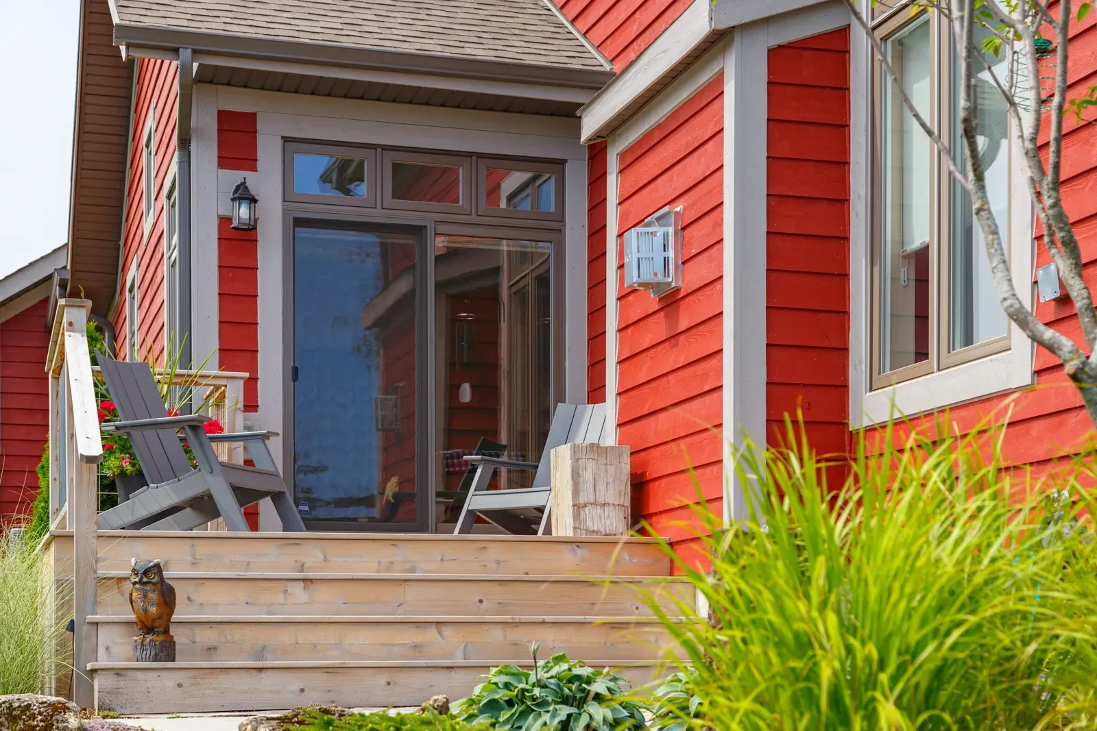 A red house with a porch and chairs in front of it.