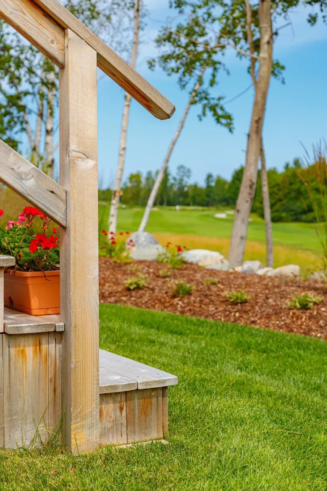 A wooden porch with stairs leading up to a golf course.