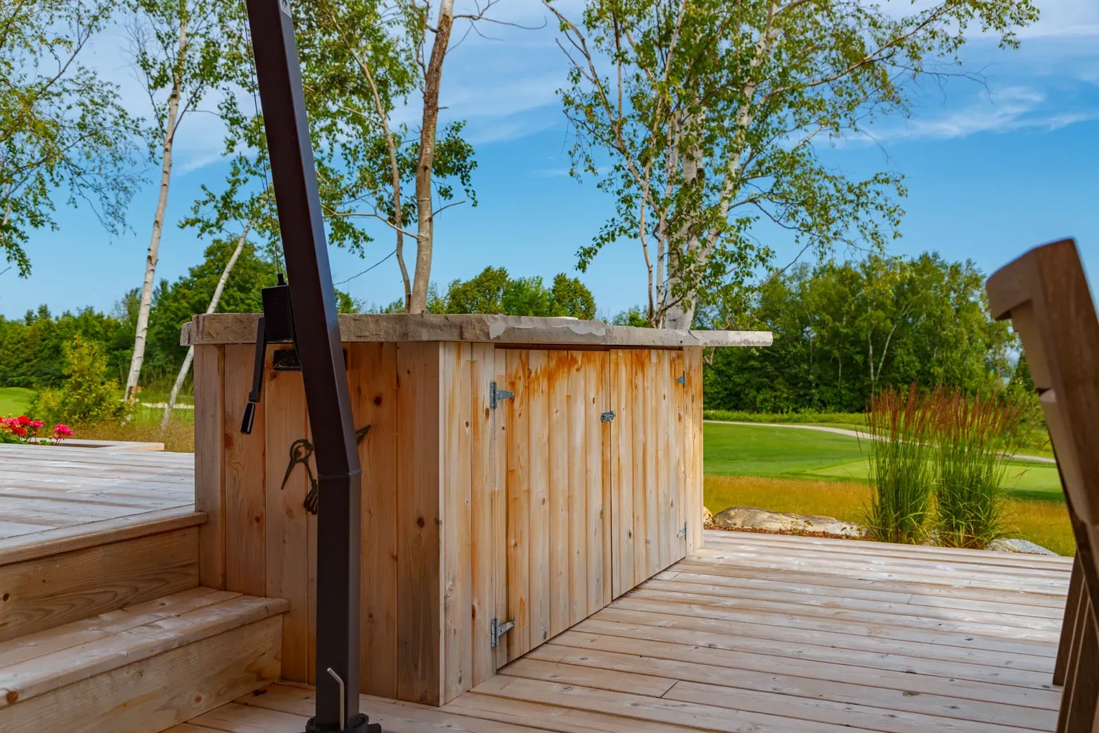 A wooden deck with stairs leading up to a wooden cabinet.
