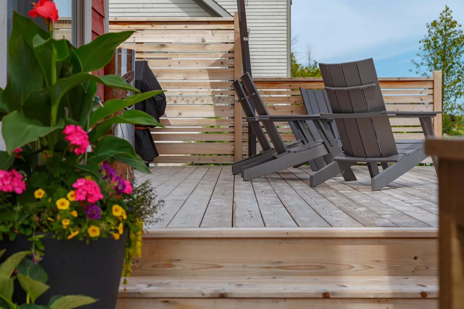 A wooden deck with chairs and flowers on it.