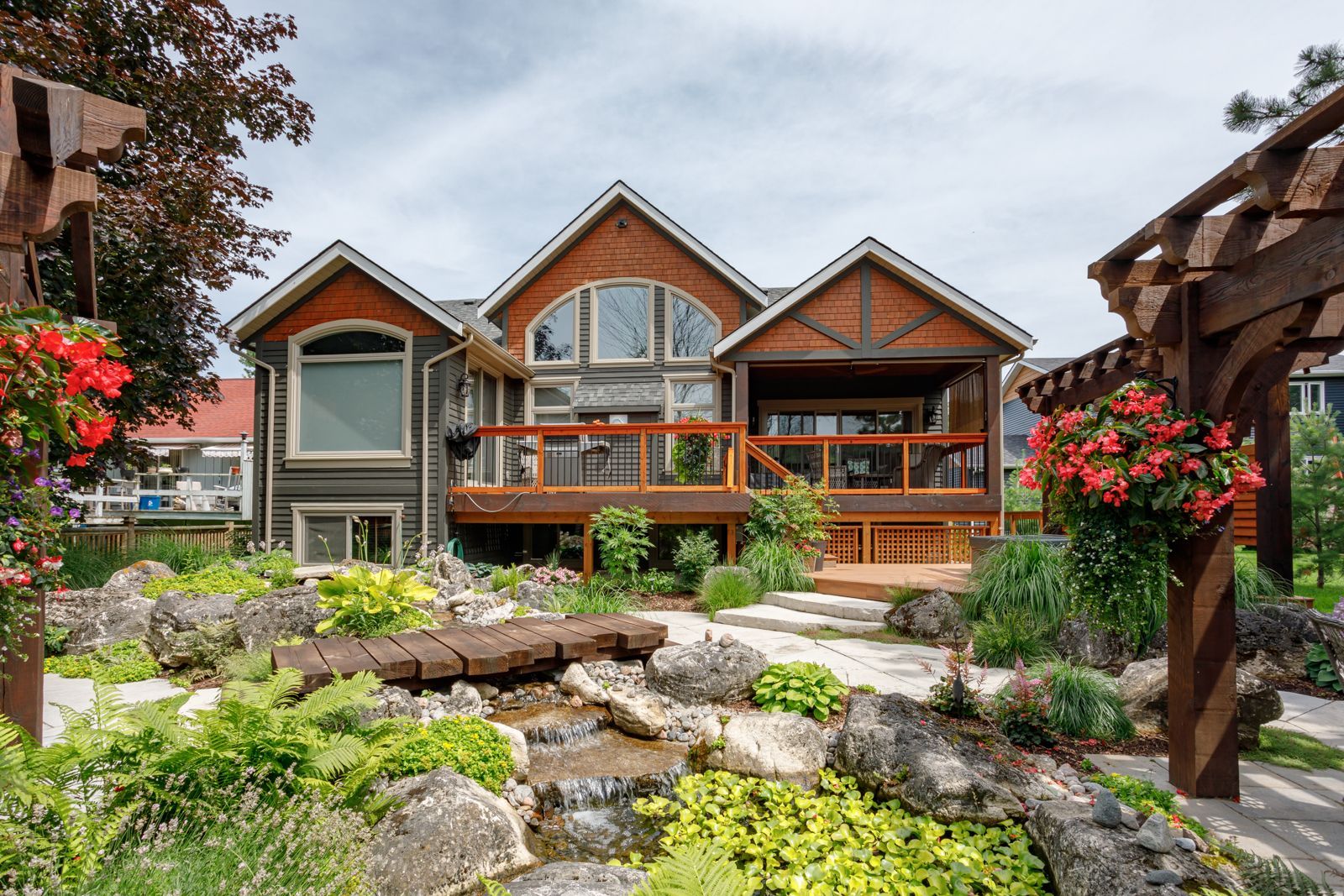 A large house with a large deck and a waterfall in the backyard.