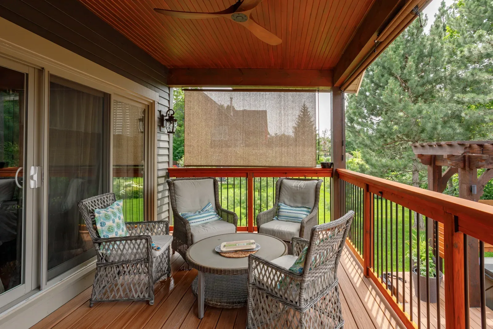 A screened in porch with wicker furniture and a ceiling fan.