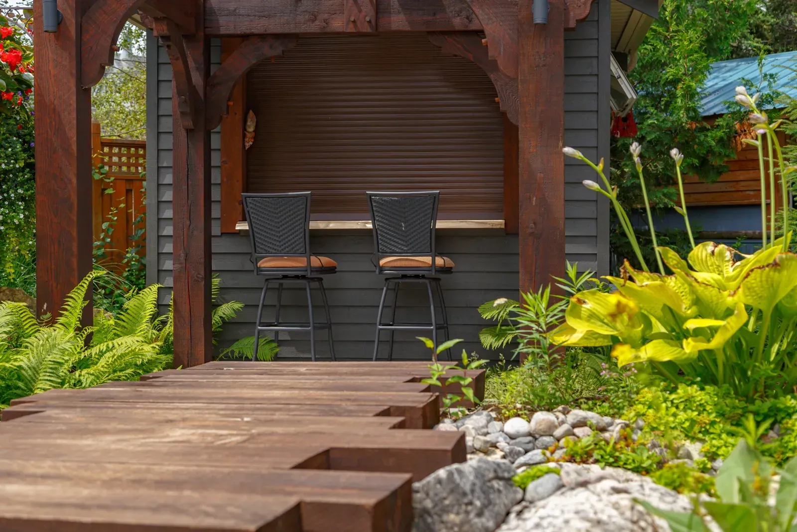 A wooden walkway leading to a gazebo with two wicker chairs.