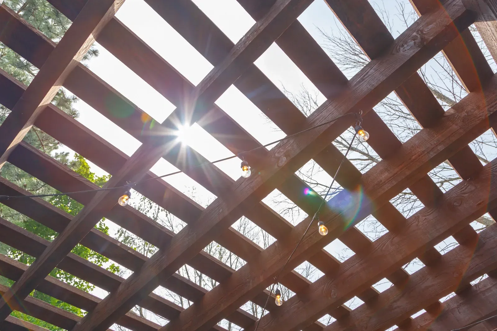 The sun is shining through the holes in the wooden structure