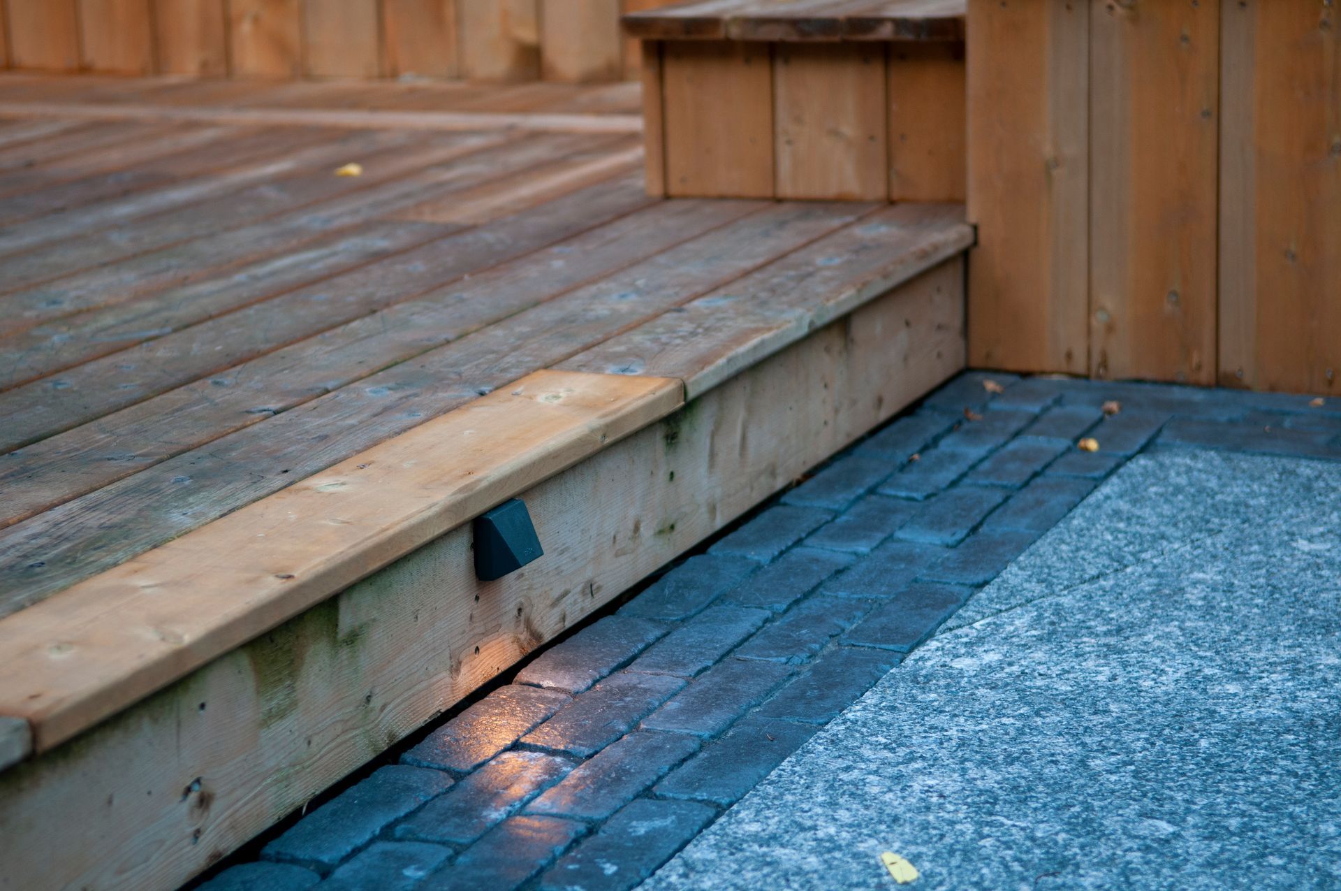 A wooden deck with a brick walkway and a wooden fence.