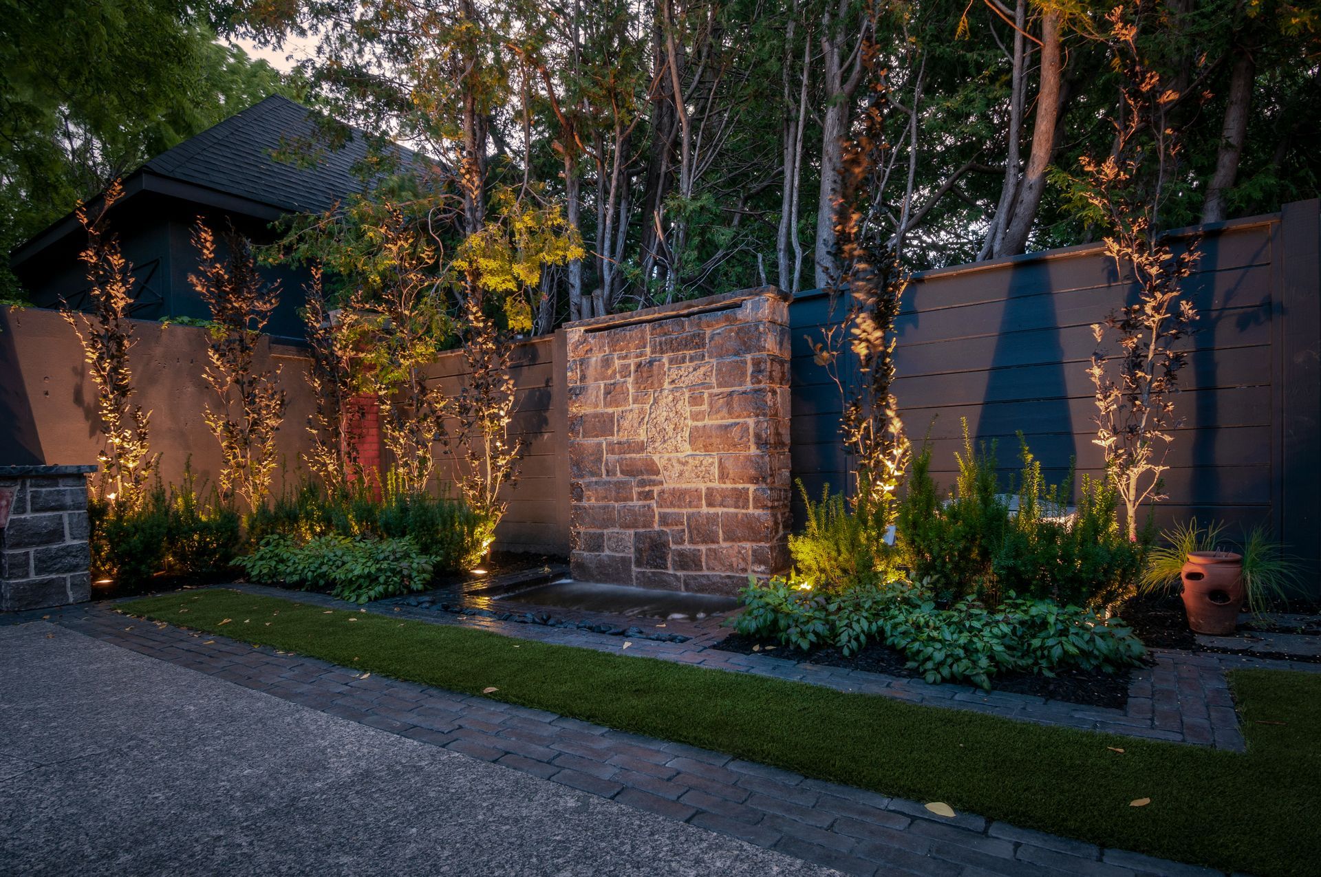 A stone wall is lit up at night in a garden.
