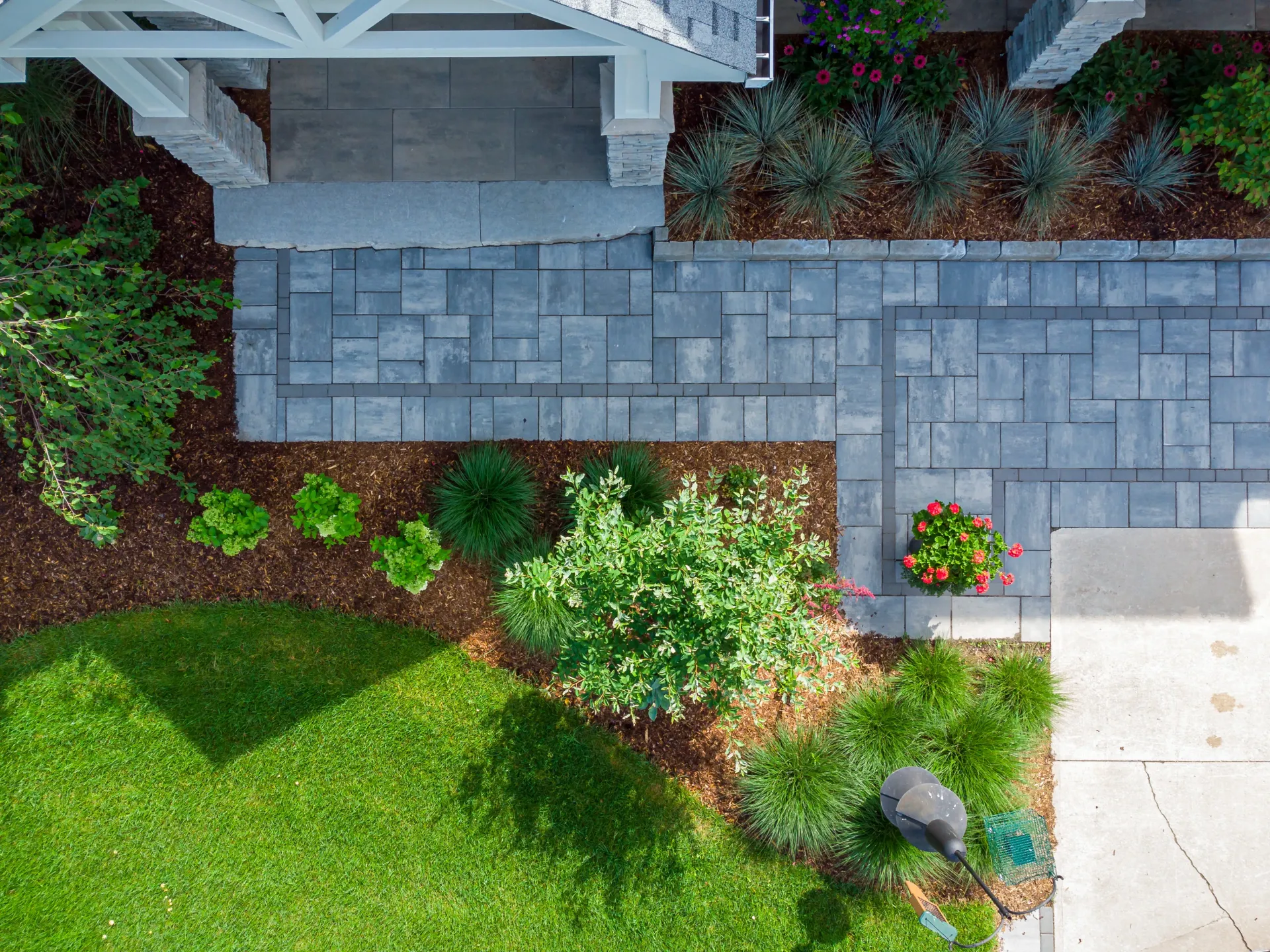 An aerial view of a lush green lawn and a walkway leading to a house.