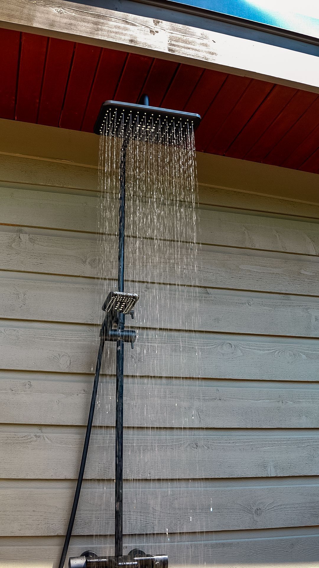 A shower head is hanging from the roof of a building