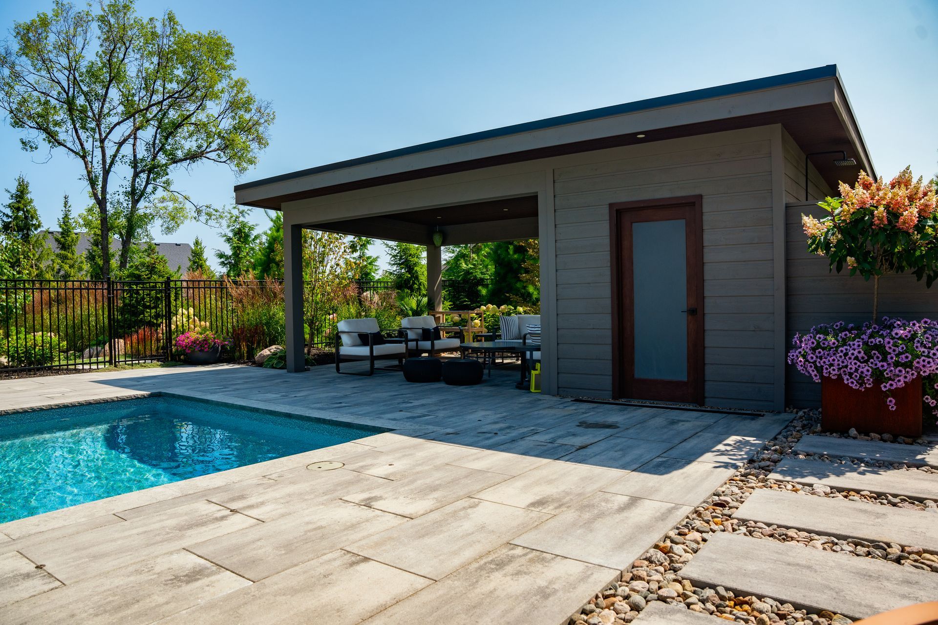 There is a swimming pool in the backyard with a shed in the background.