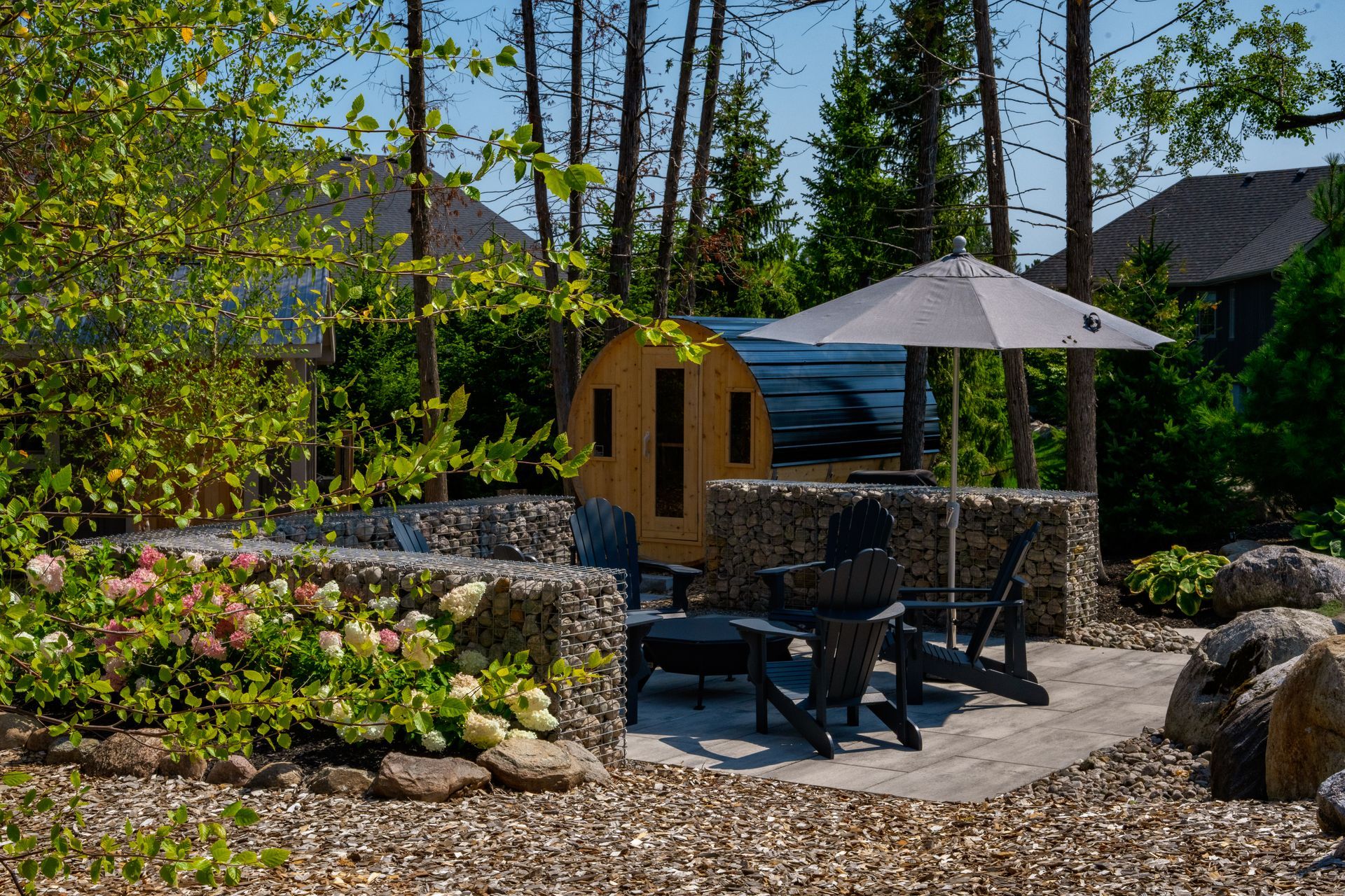 A patio with chairs , umbrellas and a sauna in the background.