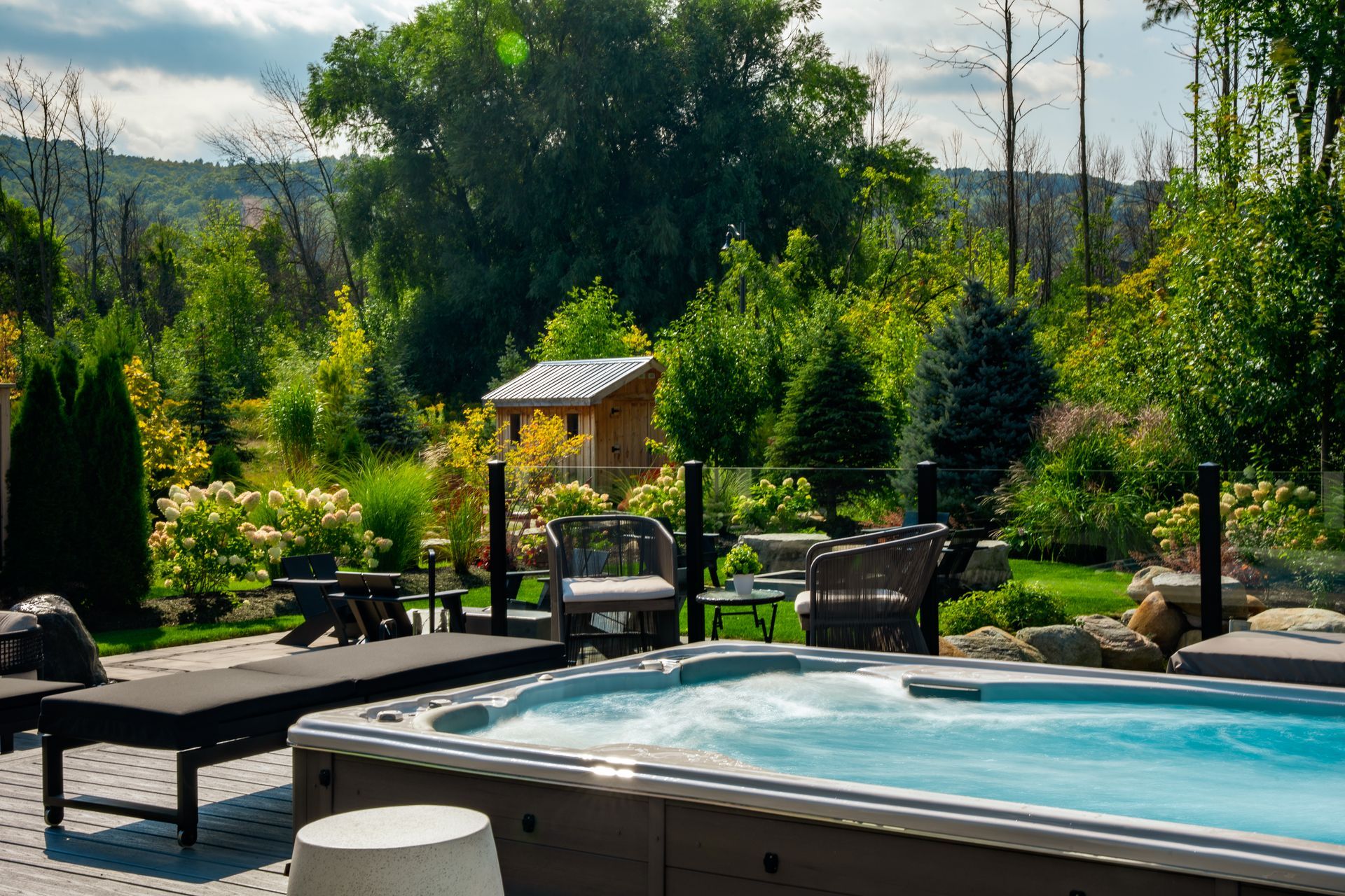 A hot tub is sitting on a patio next to a lush green garden.