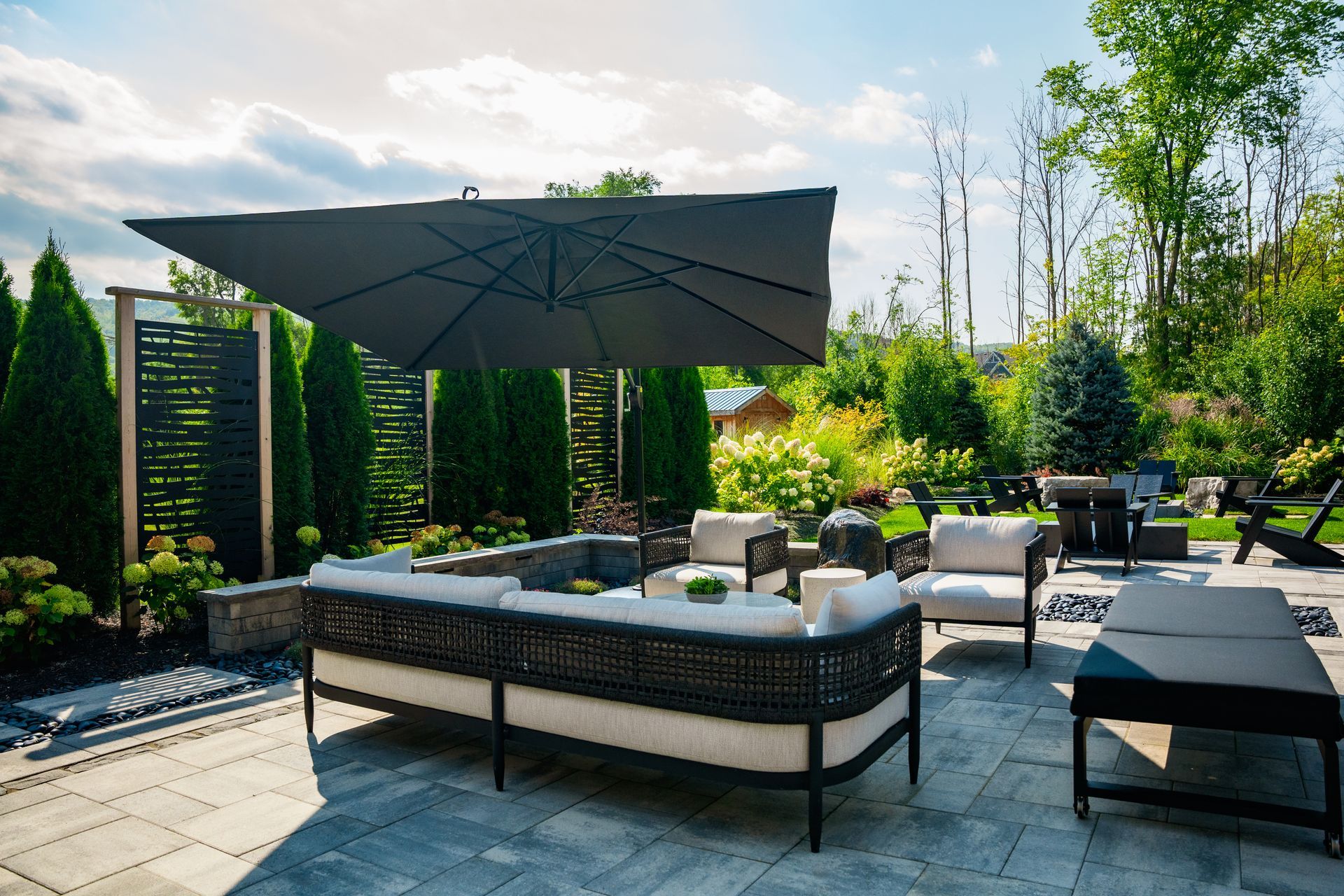 A patio with a couch and chairs under an umbrella.