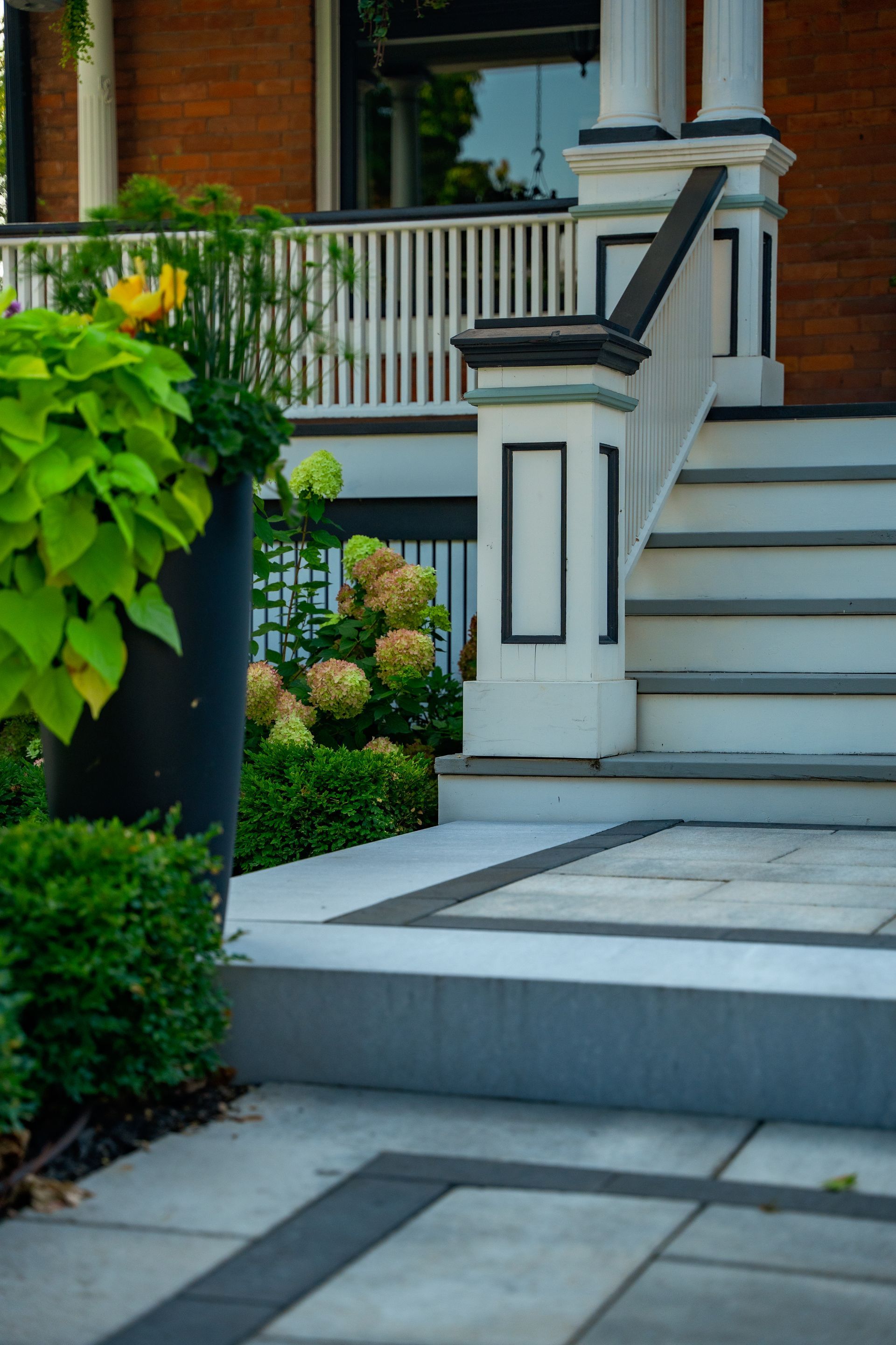 A porch with stairs and a potted plant in front of it.