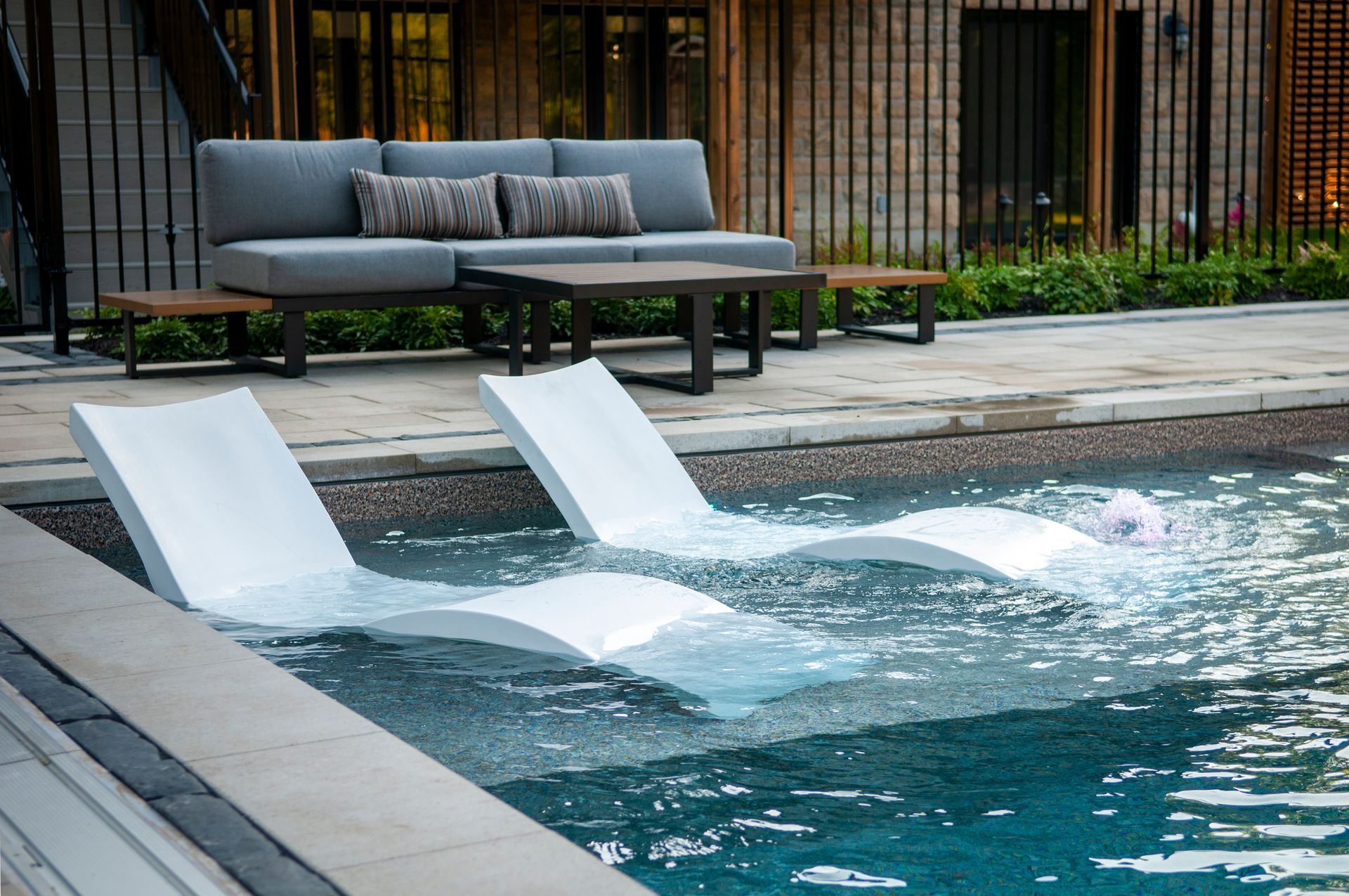 Two white lounge chairs are floating in a swimming pool.