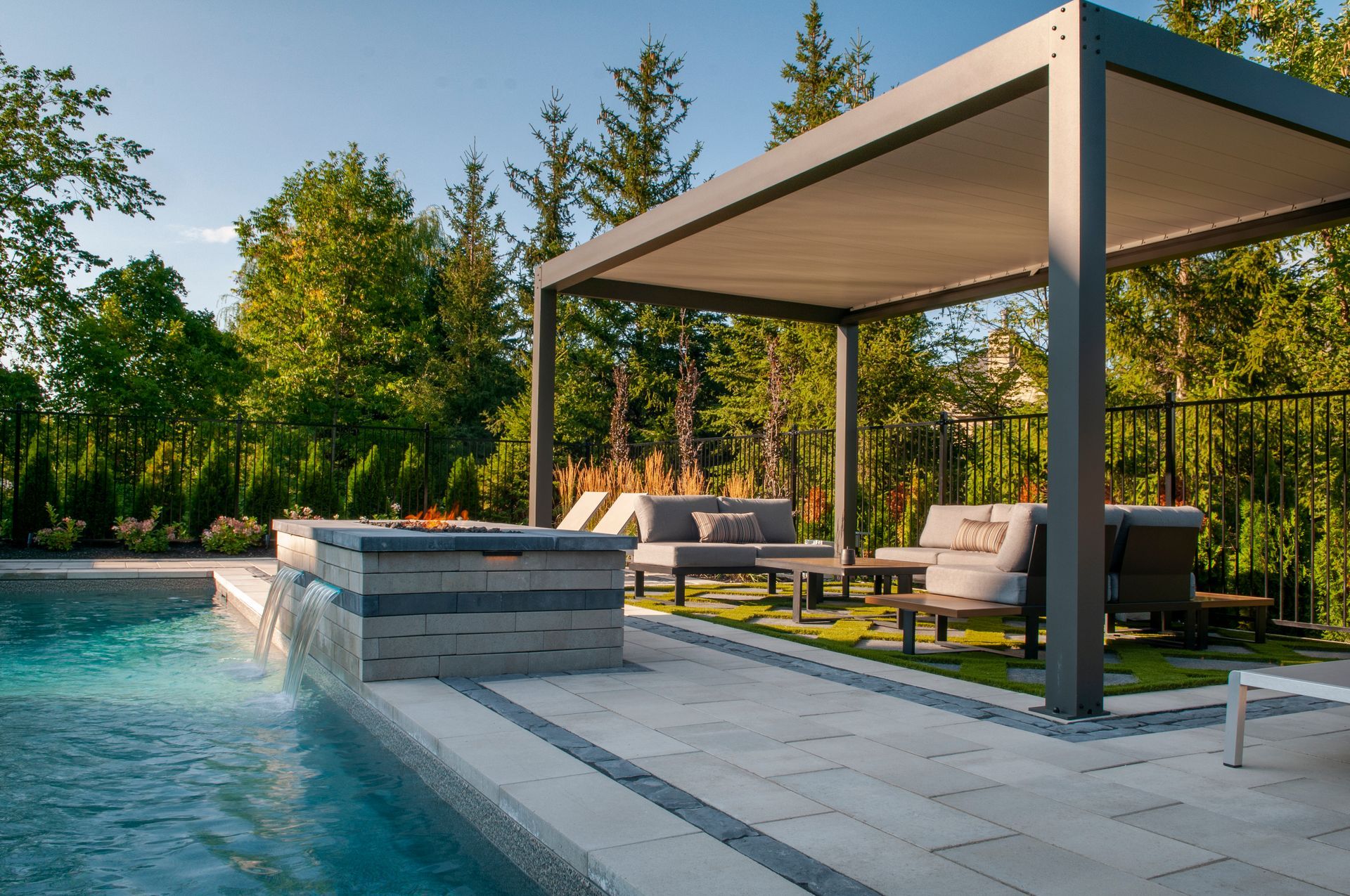 A patio with a pergola overlooking a swimming pool.
