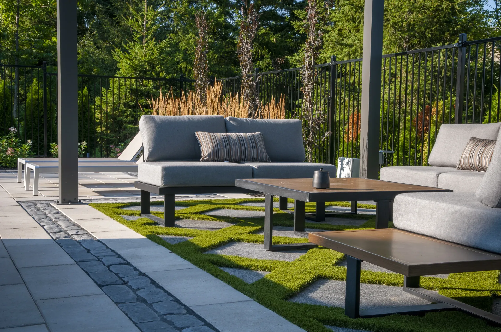 A patio with a couch , chairs , tables and a pergola.