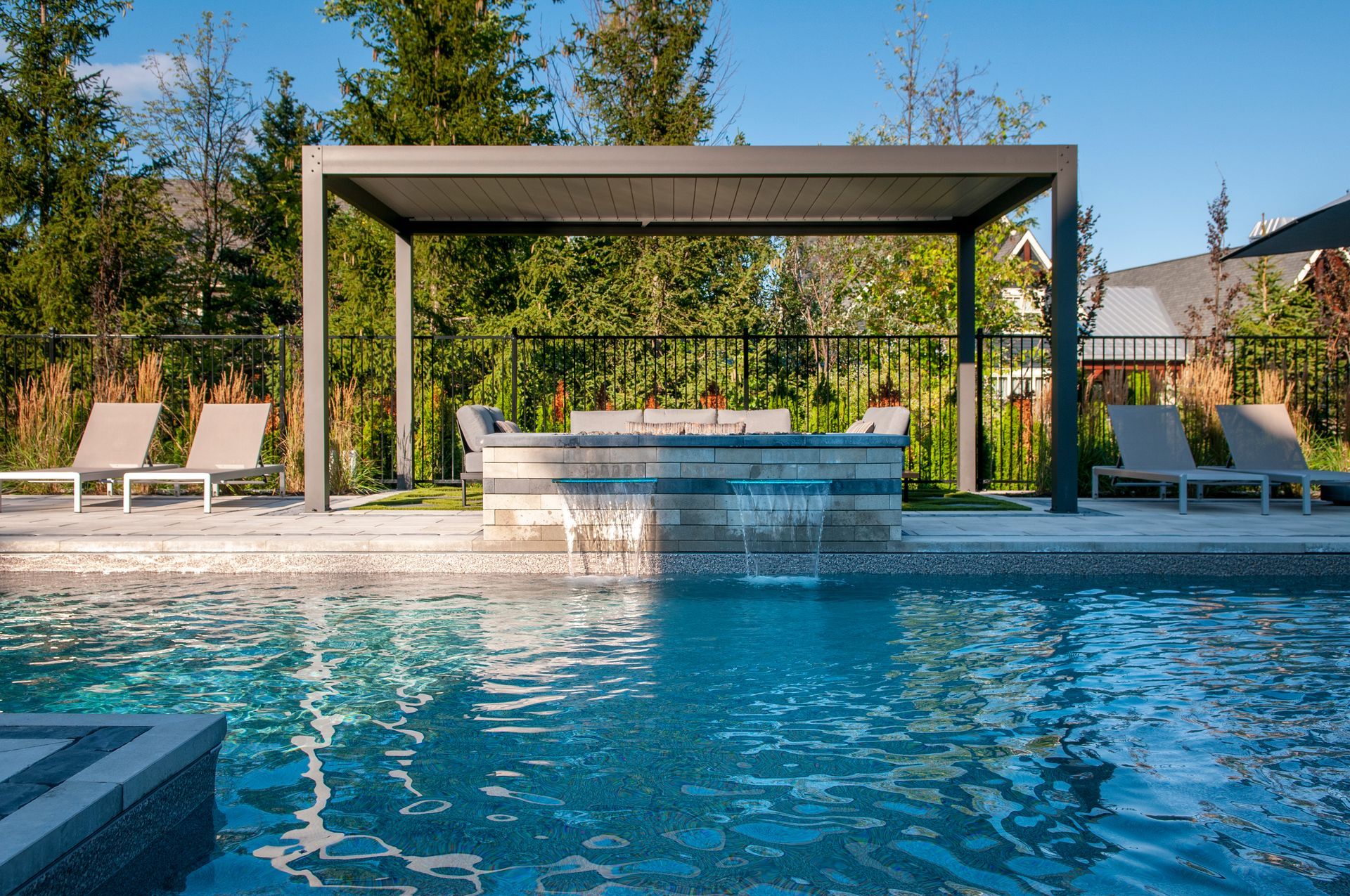 A large swimming pool with a pergola and chairs around it.