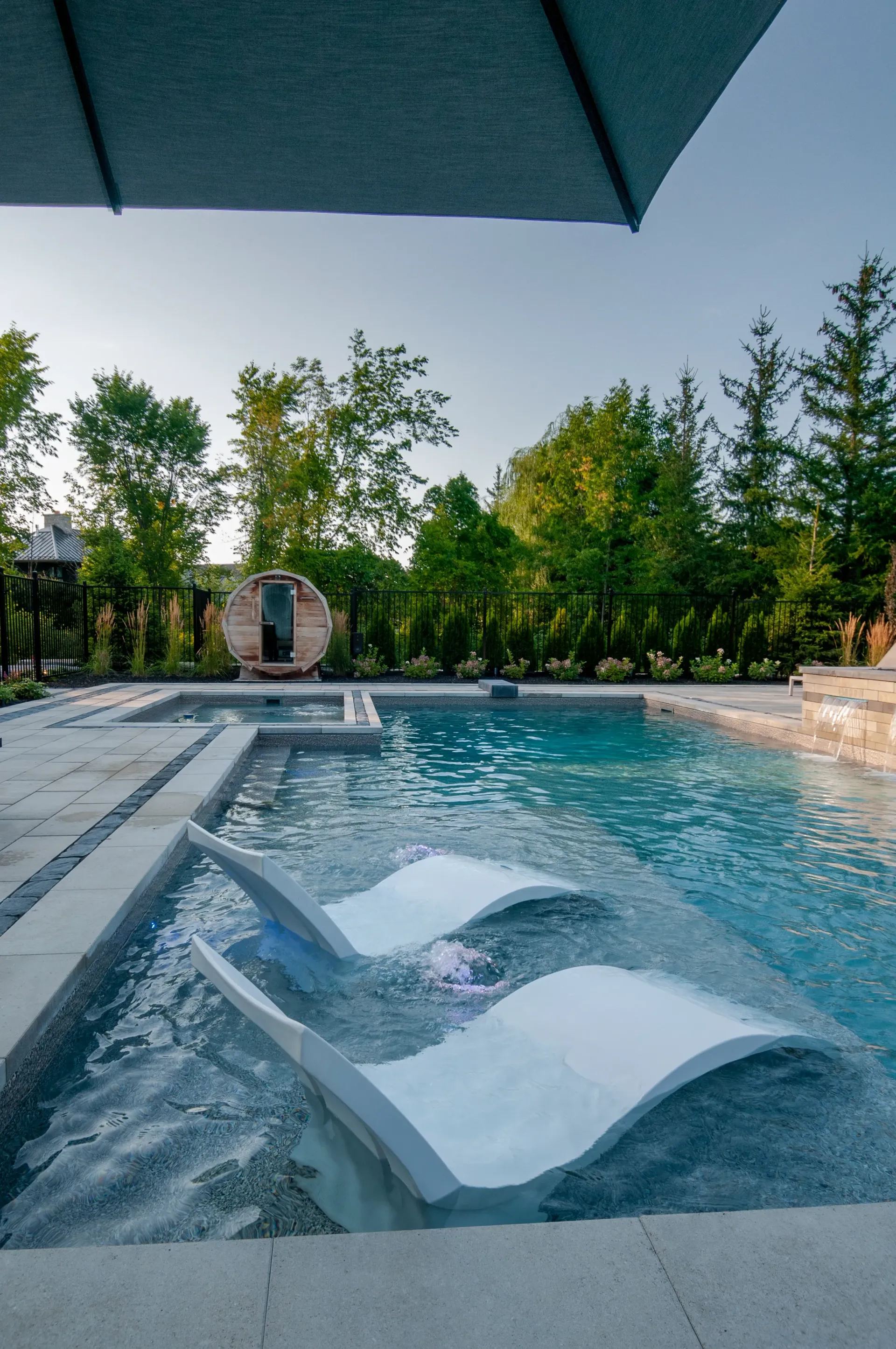 A swimming pool with a chair and umbrella in it