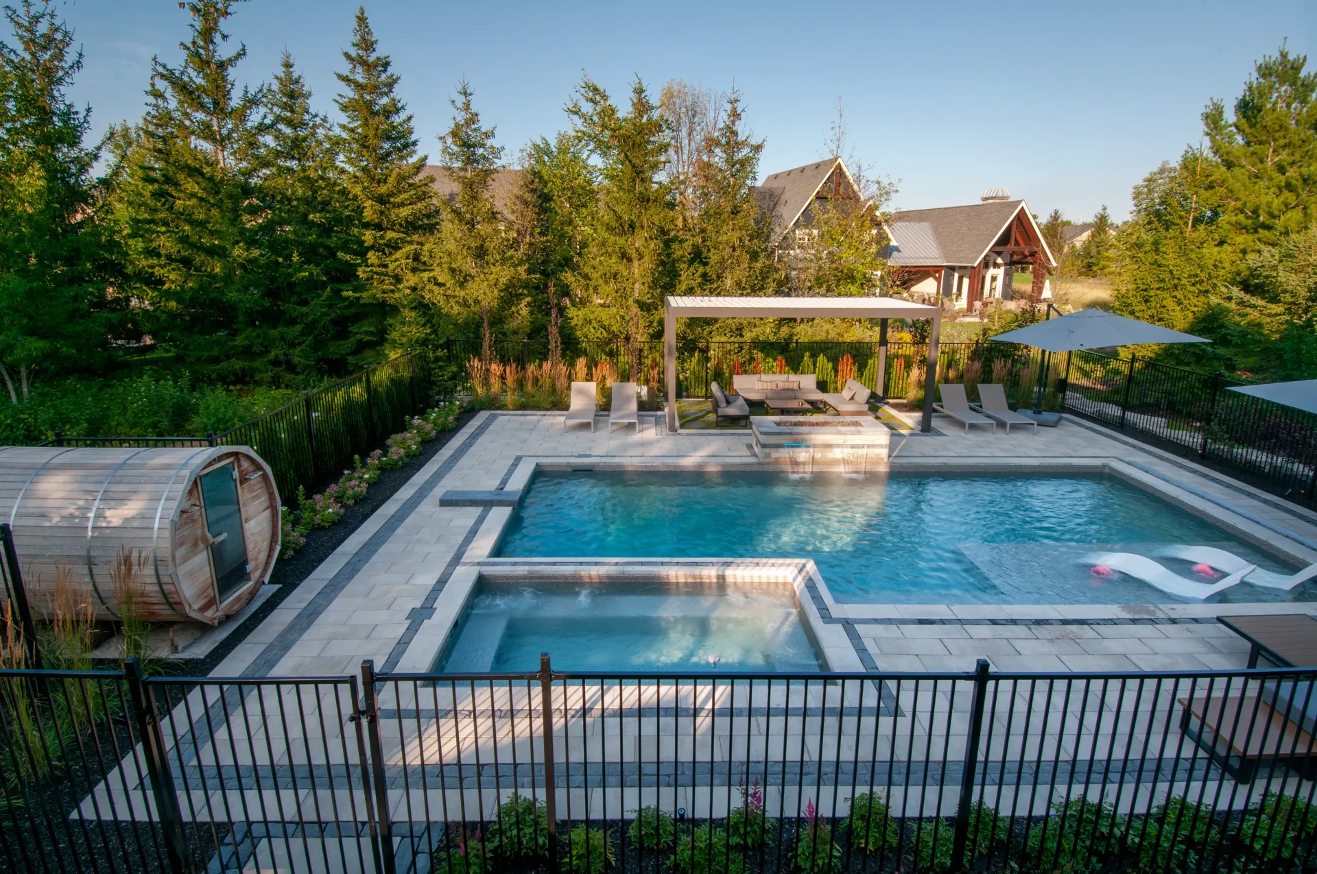 There is a large swimming pool in the backyard of a house surrounded by trees.