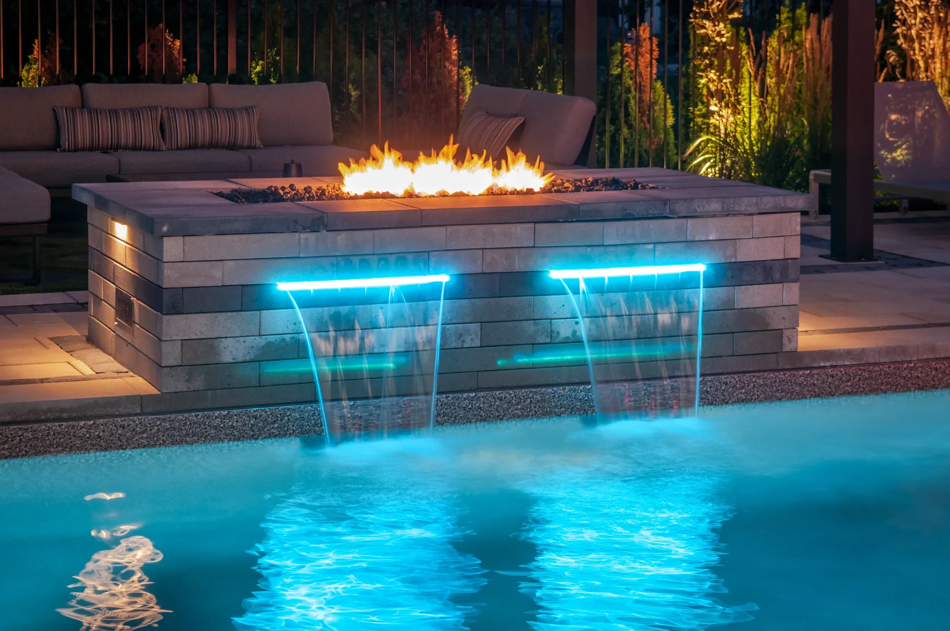 There is a fire pit in the middle of the pool with a waterfall.