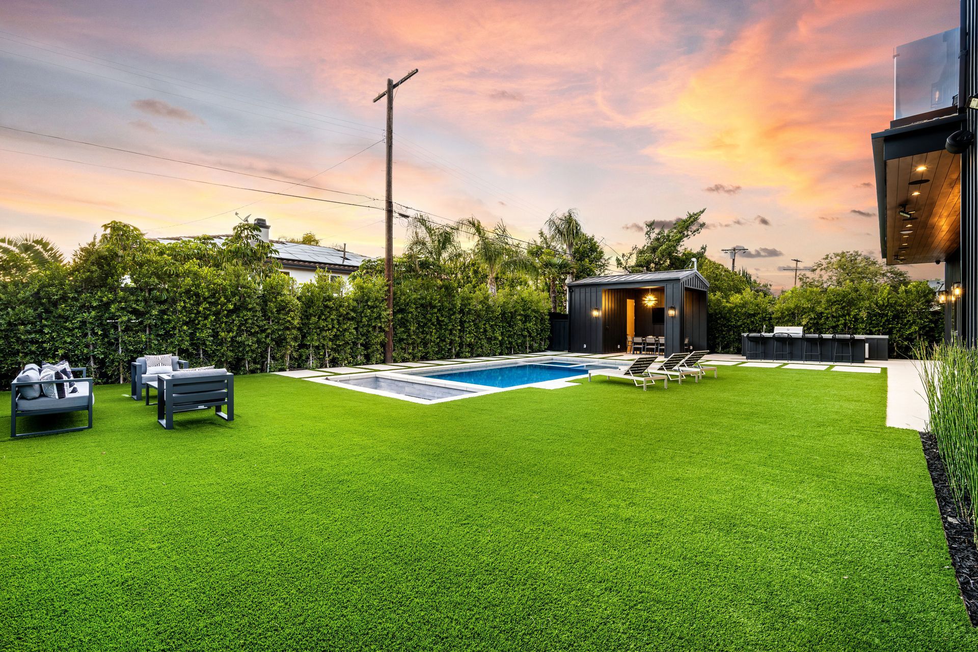 A large lawn with a swimming pool in the backyard of a house.