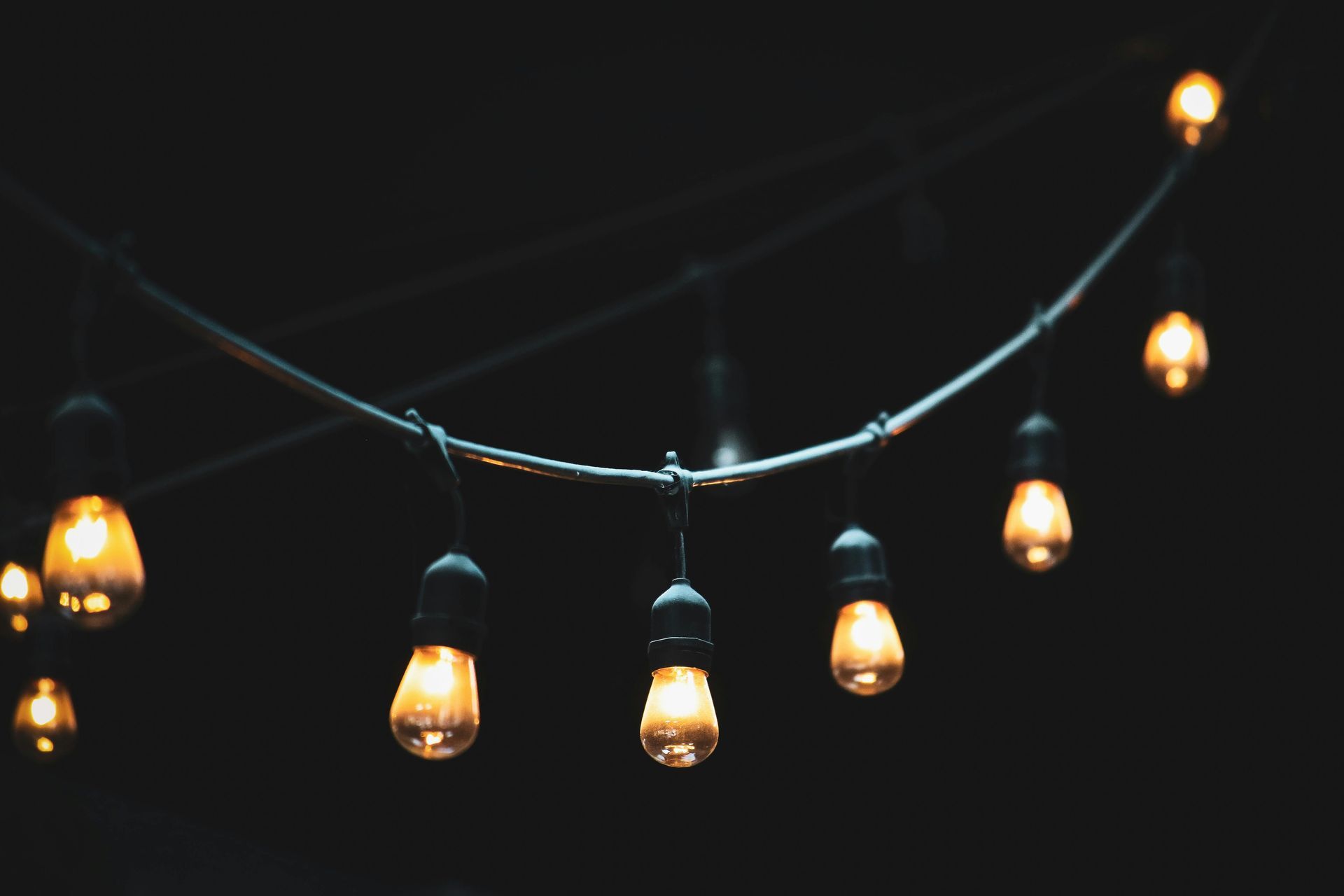 A string of lights hanging from a wire in the dark.