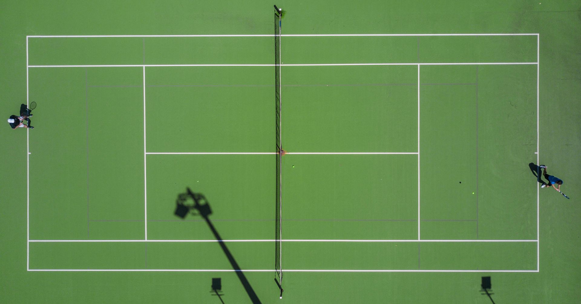 An aerial view of a tennis court with people playing tennis