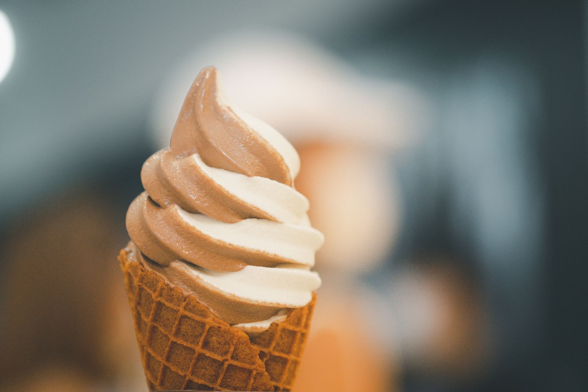 Un tourbillon de glace molle au chocolat et à la vanille dans un cornet gaufré sur un fond légèrement flou.
