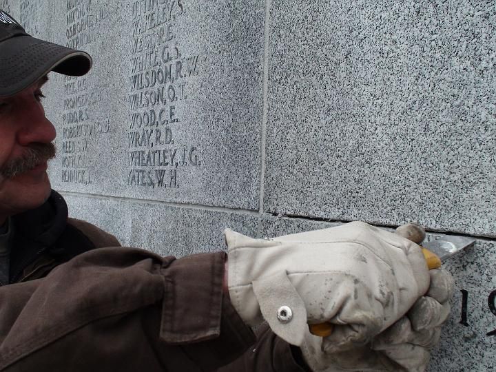 a man wearing a hat and gloves is working on a wall with the name wilson written on it