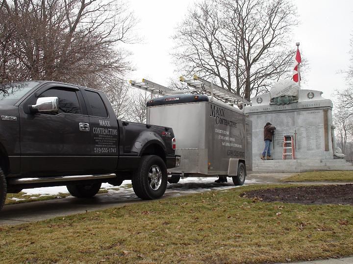 two trucks from max contracting are parked in front of a monument