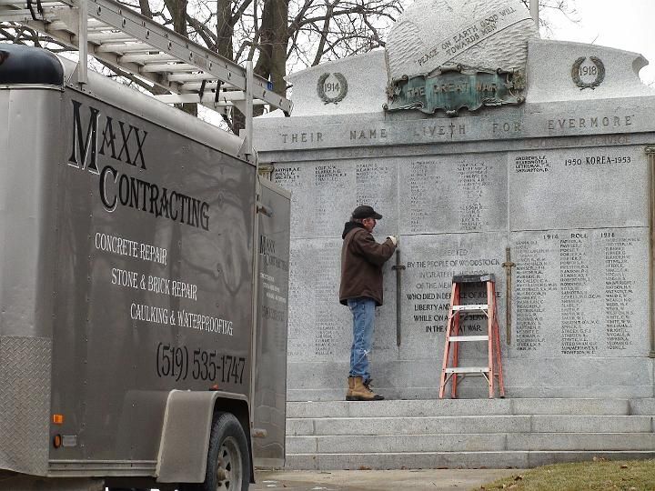 a man is working on a wall next to a maxx contracting truck