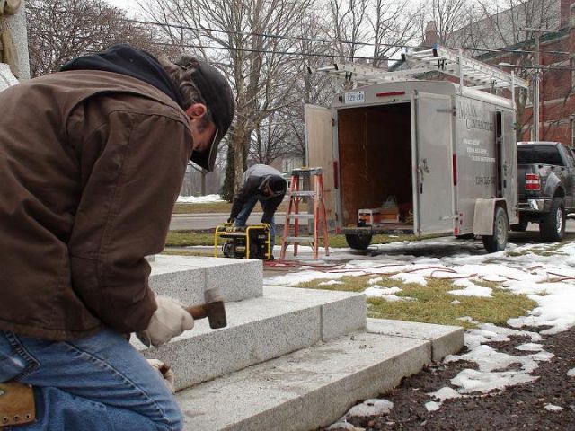 a man is working on a set of stairs in front of a trailer that says mason concrete