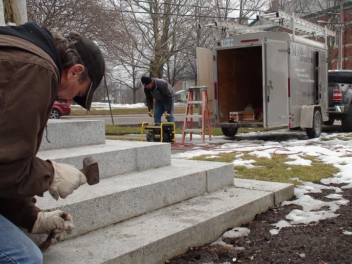 a man is working on a set of stairs next to a trailer that says mason construction