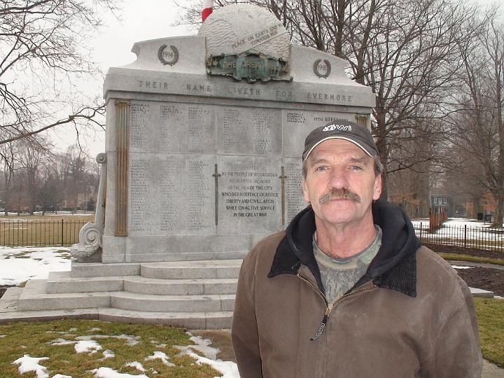 a man stands in front of a memorial that says their name lived for everyone