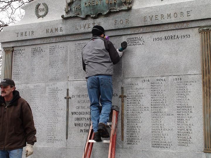 a man standing on a ladder in front of a wall with the words 