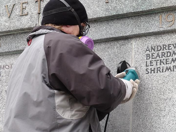 a man wearing a gas mask is working on a wall with the name andrew beard on it