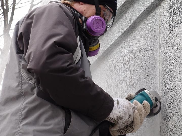 a man wearing a gas mask is using a grinder on a wall