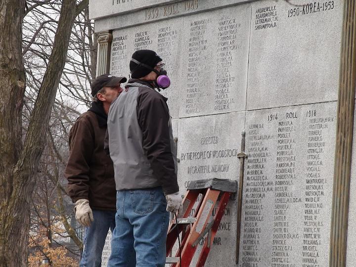two men wearing gas masks are working on a memorial