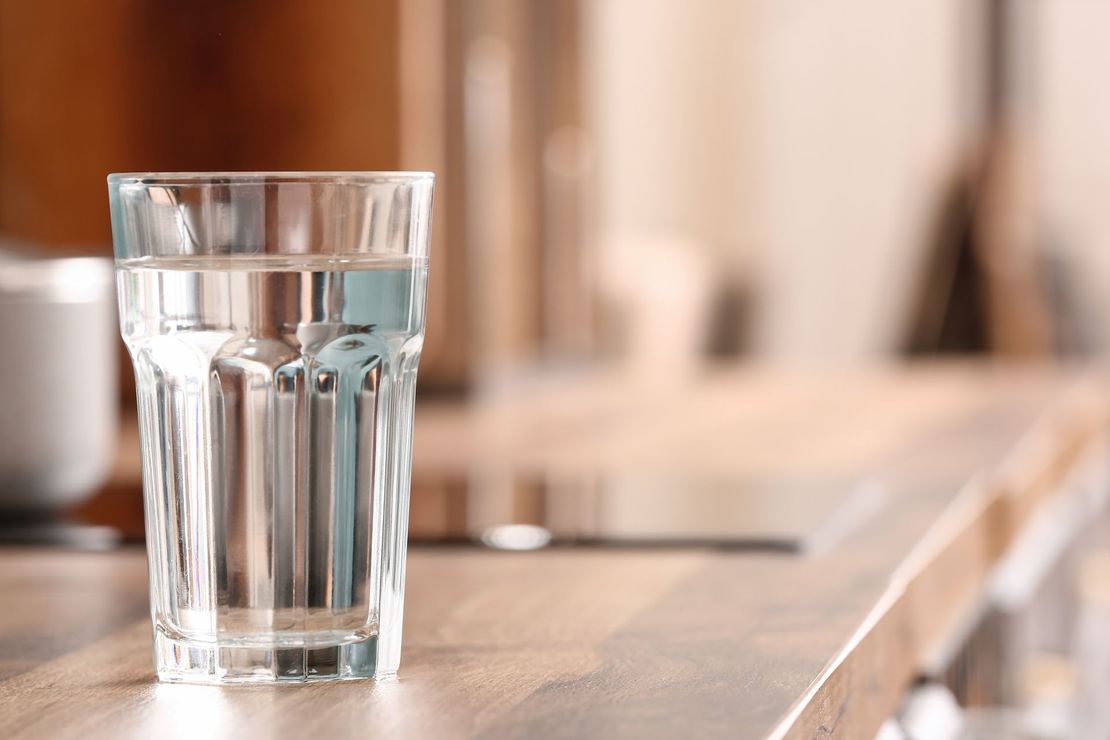 A glass of water on a sunlit tabletop in a cafe-like setting