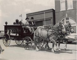 A black and white photo of a horse drawn carriage.