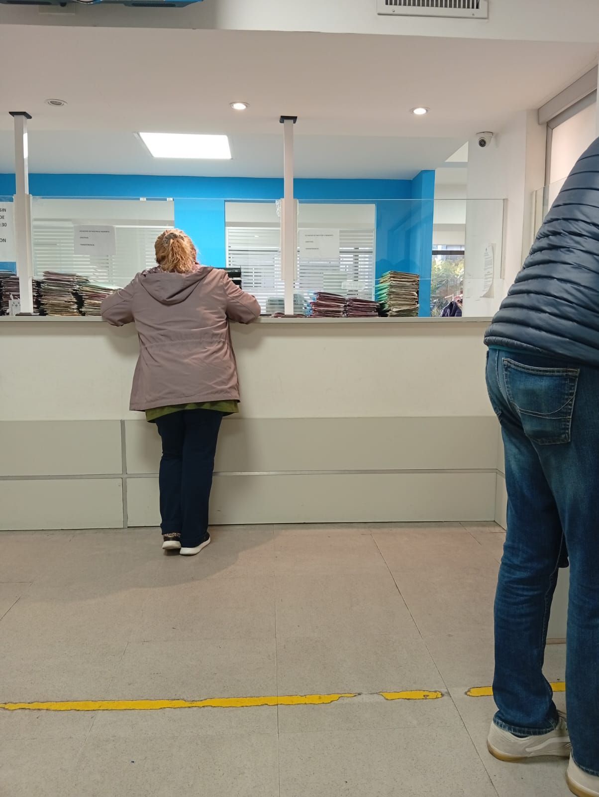 Personas de pie en un mostrador de atención al cliente en una oficina o tienda luminosa