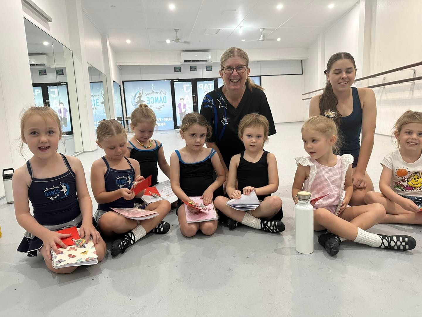 A Group Of Young Girls Are Sitting On The Floor In A Dance Studio — International Dance Affair In North Mackay, QLD