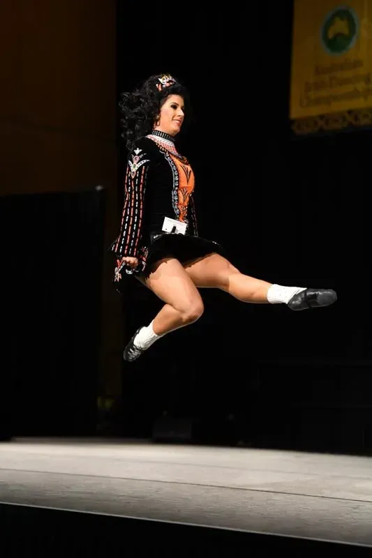 A Woman In A Black Dress Is Jumping In The Air — International Dance Affair In North Mackay, QLD