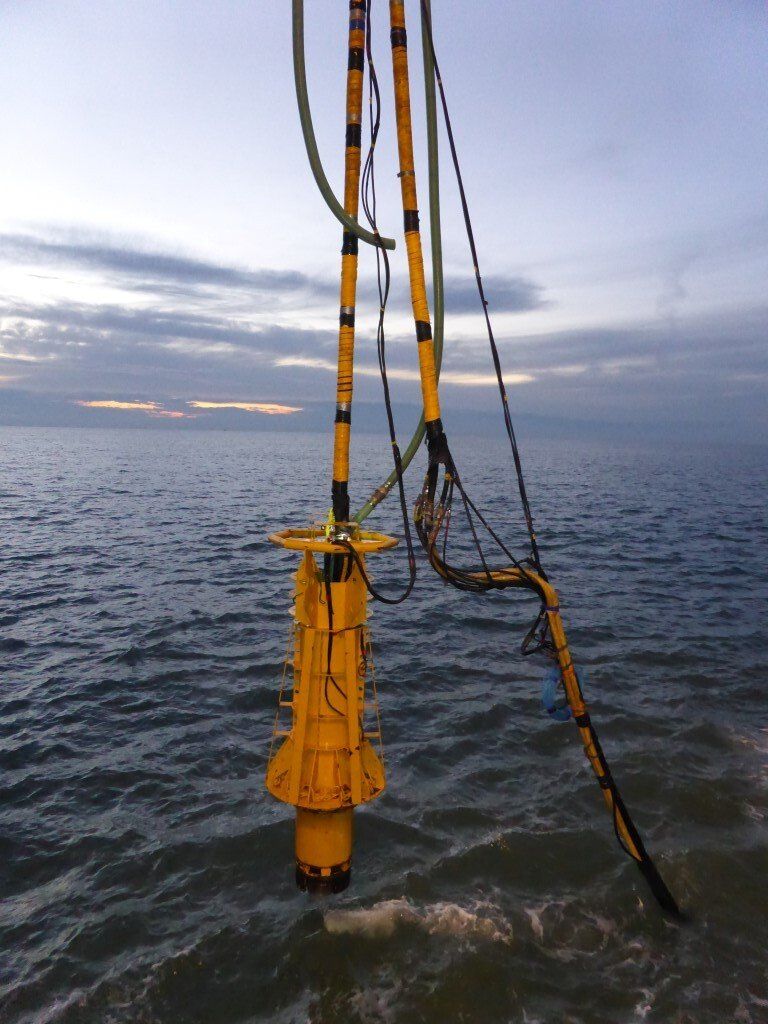 Yellow marine equipment extending into the ocean, set against a cloudy sky.