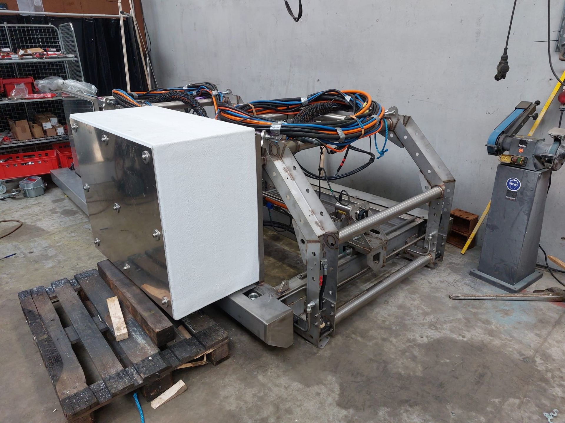 A large machine with a white box on a wooden pallet, in a workshop setting.