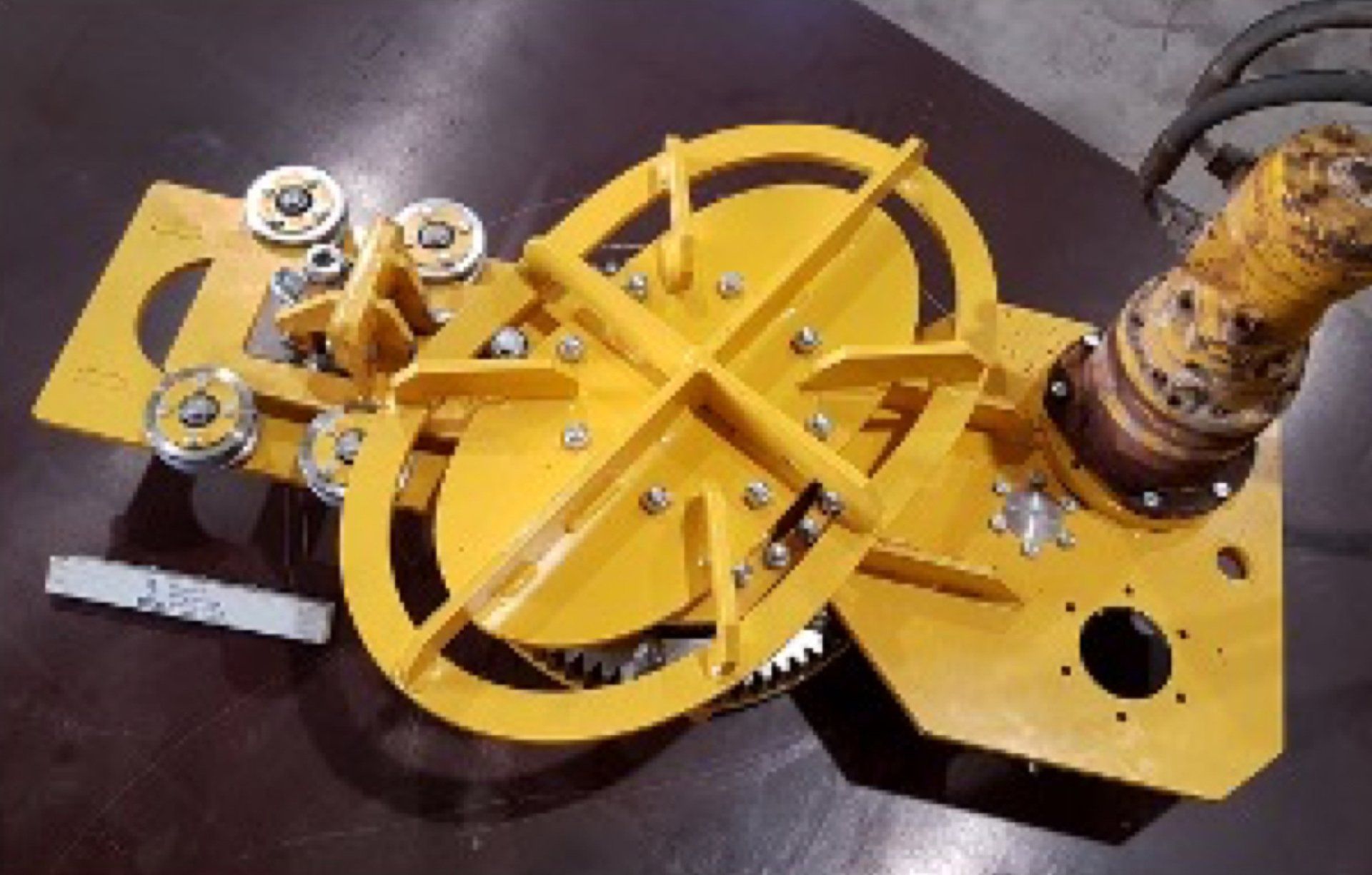 Yellow elliptical AWJ cutting tool industrial machine with gears, pulleys, and an arm.