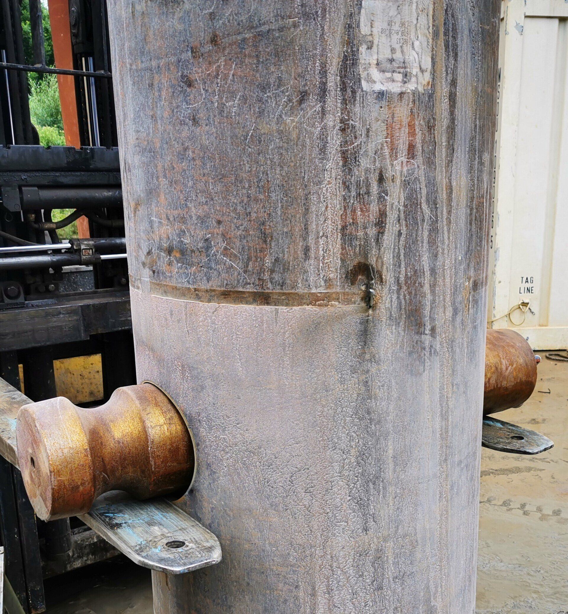 Large metal cylinder with rust and a handle.