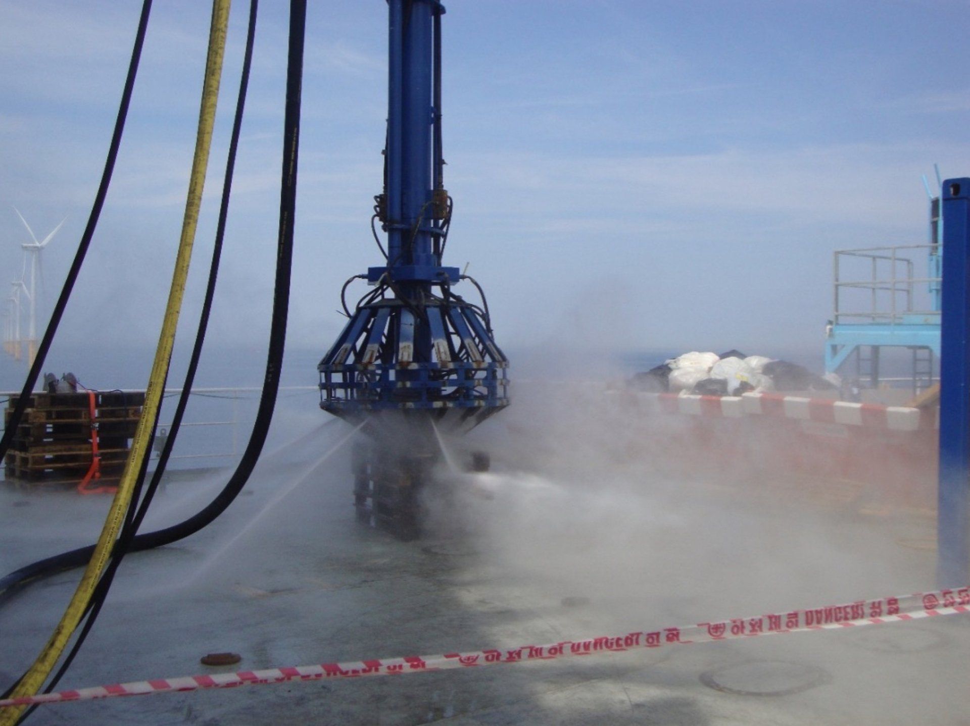 A large blue industrial crane spraying water.