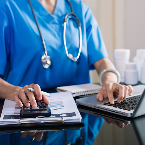 A nurse is using a calculator and a laptop computer